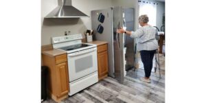 woman with walker opening side-by-side fridge in her kitchen